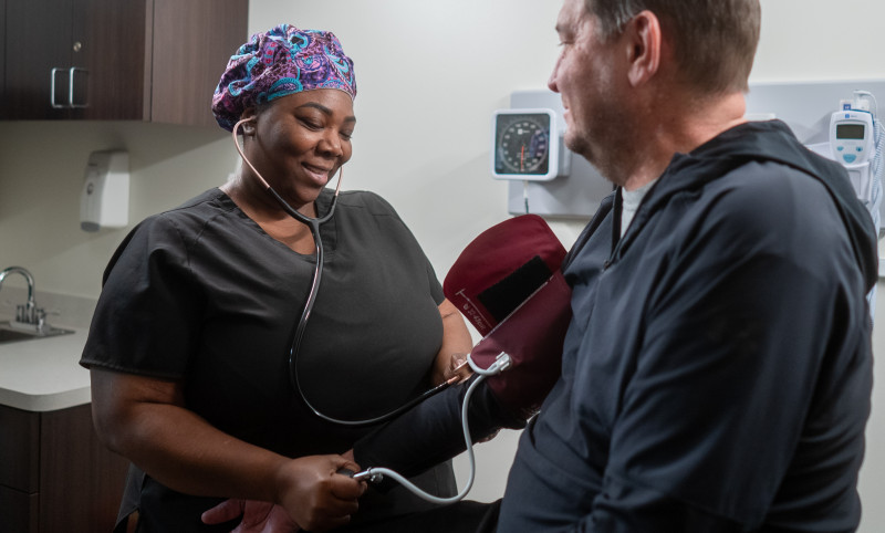 a nurse checks a patient's blood pressure.