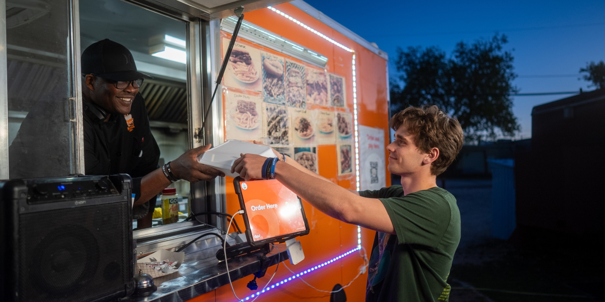 food truck owner handing a customer a takeaway food container