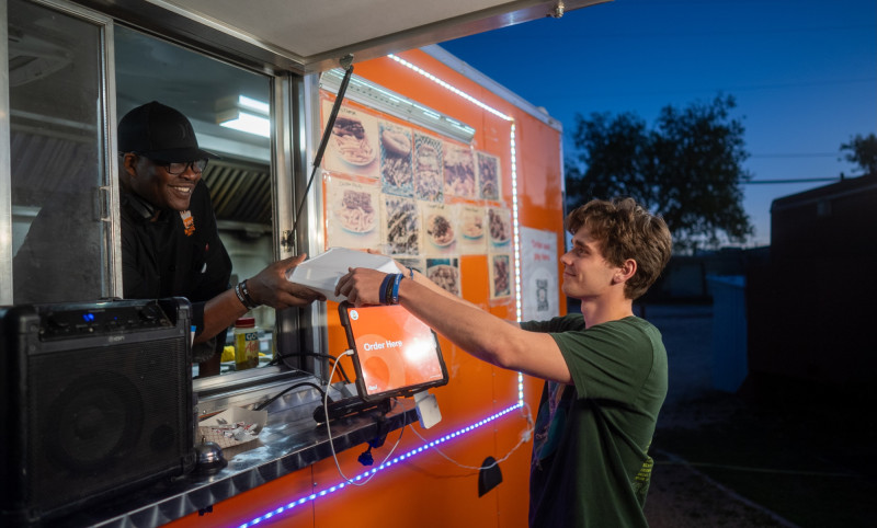 food truck owner handing a customer a takeaway food container