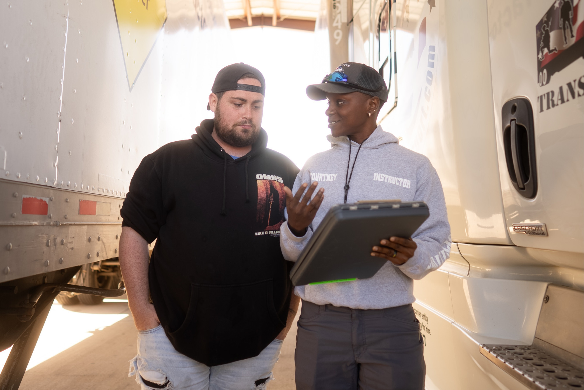 two people looking at a clipboard by a large truck
