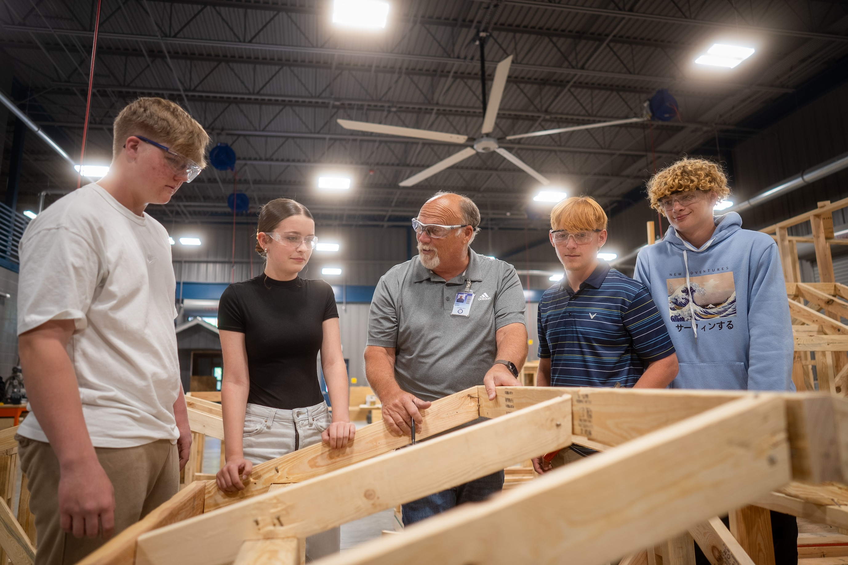 students with teacher looking at wooden frame