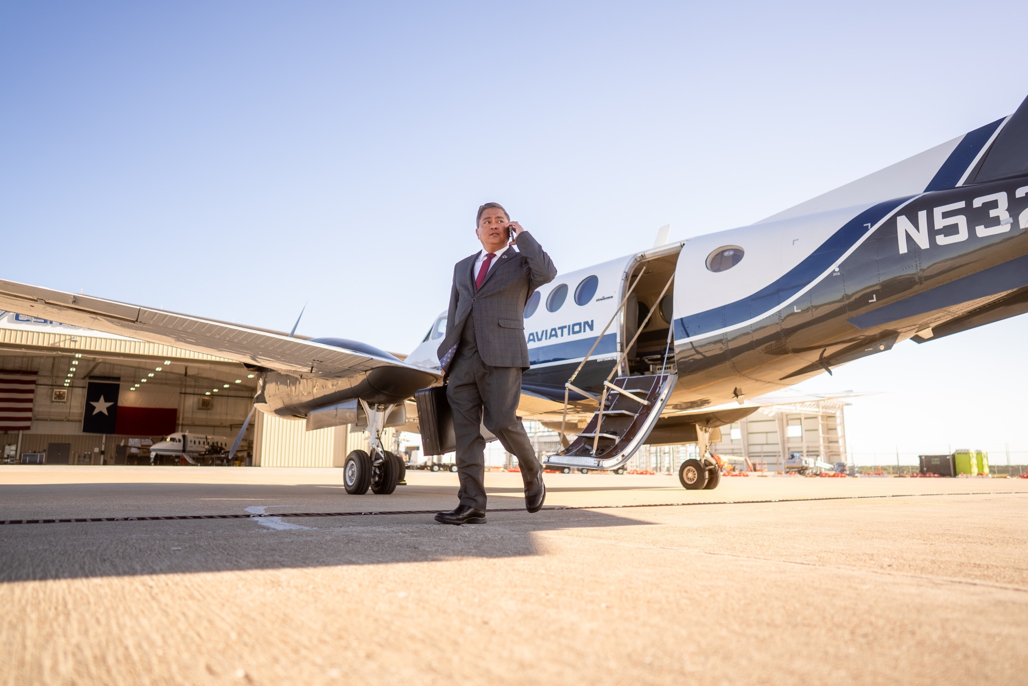 business man exiting a private jet while on his cellphone and holding a briefcase